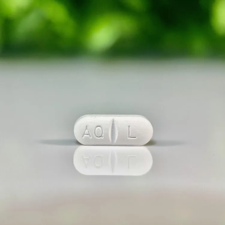 White Apoquel 16 mg tablet with “AQ L” imprint and scored center line, displayed on reflective surface.